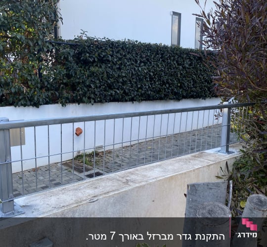 גדר מתכת עם עמודים על קיר בטון